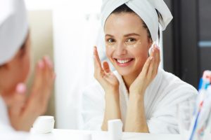 Corretta skincare routine - donna allo specchio con crema